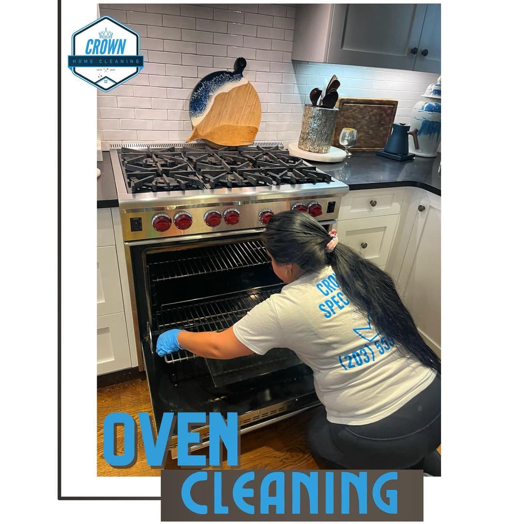 Person cleaning an oven, wearing gloves, in a modern kitchen with stainless steel appliances.